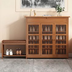 a wooden cabinet sitting next to a wall with shoes on it and a plant in the corner