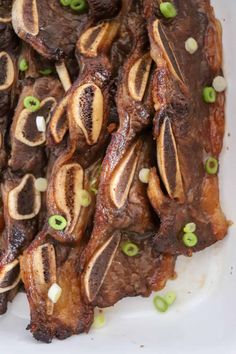 the meat is cooked and ready to be eaten on the plate with green onion garnishes