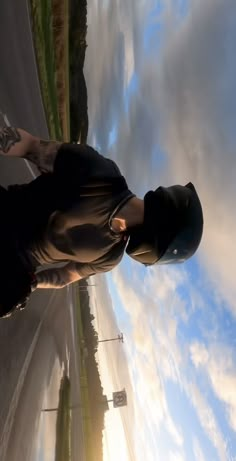 a man standing on the side of a road with his skateboard in front of him