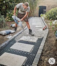 a man is working in the garden with cement and concrete pavers on the ground