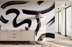 an abstract black and white painting on the wall next to a dresser with a lamp