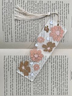 two bookmarks with flowers and tassels on top of an open book page