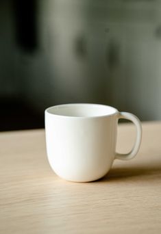 a white cup sitting on top of a wooden table