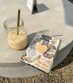 a book sitting on top of a table next to a jar filled with liquid and a straw