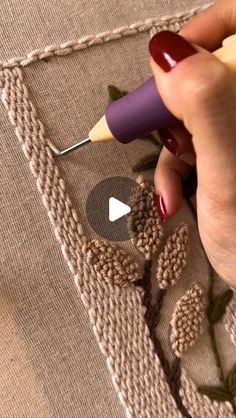 someone is using a crochet hook to stitch the design on a piece of fabric