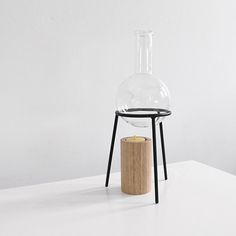 a glass vase sitting on top of a table next to a wooden candle holder with a black metal stand