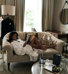 a woman laying on top of a couch in a living room next to a window