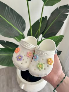 someone holding up their white crocs with colorful flowers on the inside and outside