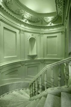 a staircase in an old building with green walls and white trim around the railings