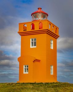 an orange lighthouse on top of a hill