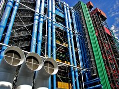 pipes are stacked on top of each other in front of a large building that is under construction