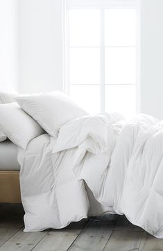 an unmade bed with white sheets and pillows