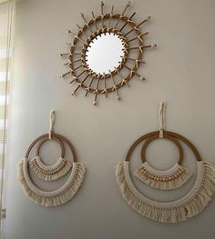 two circular mirrors hanging on the wall next to some tassels and other accessories