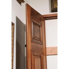 an open wooden door in the corner of a room with white walls and wood trim