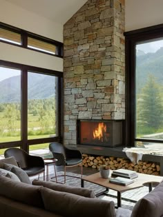 a living room filled with furniture and a fire place in front of a window that looks out onto the mountains