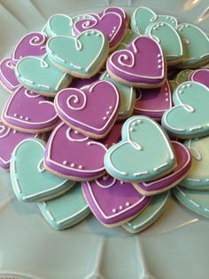 some heart shaped cookies on a plate with blue and purple icing in the shape of hearts