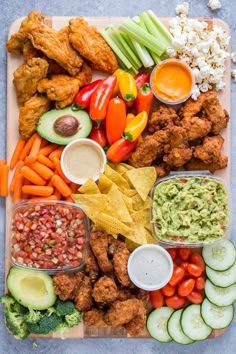 a platter filled with chicken, vegetables and guacamole dips next to chips