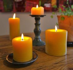 three lit candles sitting on top of a wooden table