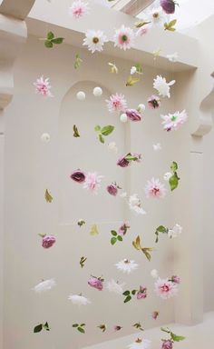 a white room with pink and white flowers hanging from it's ceiling next to a window