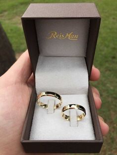 two gold wedding rings in a box with the lid open to show it's inside