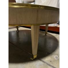 an oval table with gold trim on the top and bottom, sitting in a room