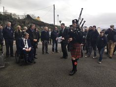 a man in a kilt playing the bagpipes at an outdoor event with people watching