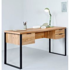 a wooden desk with two drawers and a lamp on top of it, against a white wall