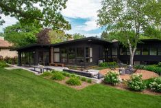 a modern home sits in the middle of a lush green yard