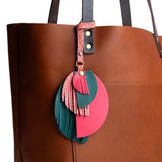 a brown bag with a pink and green tassel hanging from it's side