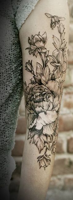 a woman's leg with flowers on it and a brick wall in the background