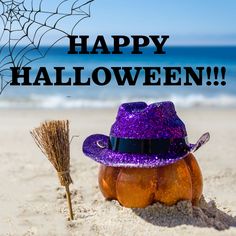 a purple hat sitting on top of a sandy beach next to a broom and spider web