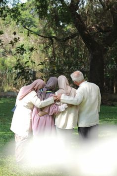 a group of people standing next to each other on a lush green forest covered field