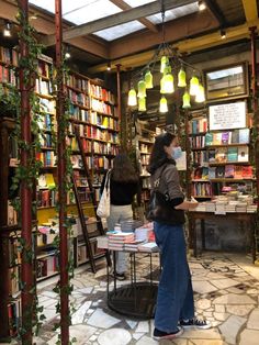 a woman standing in front of a bookshelf filled with lots of books