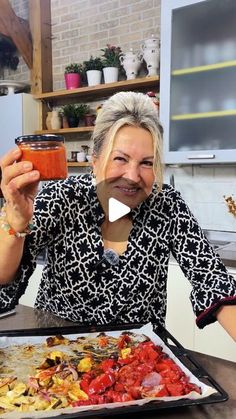 a woman holding up a glass in front of a pizza