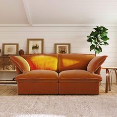 an orange couch sitting in a living room next to a table