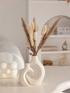 a white vase with some dried flowers in it