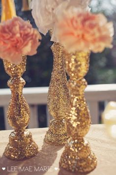 two gold vases with flowers in them on top of a table next to each other