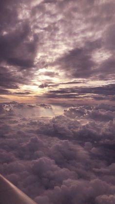 the view from an airplane looking down on clouds and sun rays in the sky above