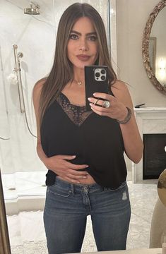 a woman taking a selfie with her phone in front of a bathroom mirror and fireplace