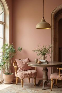 a dining room with pink walls and wooden chairs, potted plants on the table