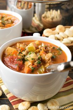 two bowls filled with soup sitting on top of a table next to crackers and bread