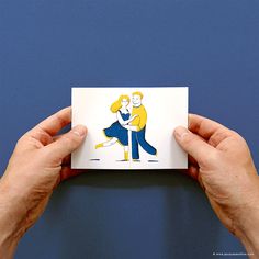 two hands holding up a card with an image of a man and woman on it