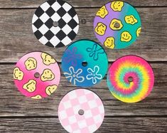 six different colored donuts with smiley faces on them, sitting on a wooden surface