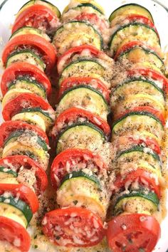 a casserole dish filled with sliced cucumbers, tomatoes and other veggies