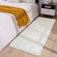 a white rug is on the floor next to a bed