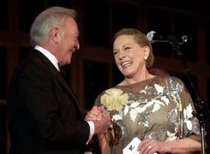 a man and woman standing next to each other in front of a microphone on stage