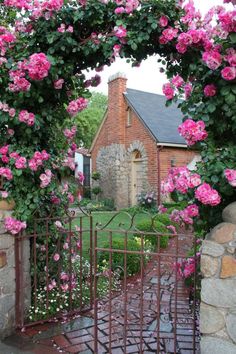 a gate with pink flowers on it and a house in the background