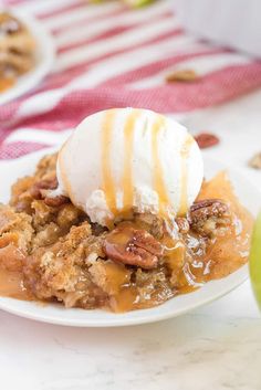 an apple crisp with ice cream on top and pecans around the edges, sitting on a white plate