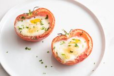 two tomatoes with eggs in them on a white plate