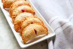 several small pastries on a white plate next to a gray towel and blue cloth